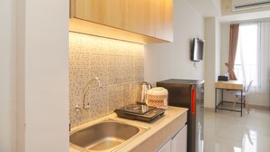 A modern kitchen with a double sink, a coffee maker, and a refrigerator. - Minimalist And Homey Studio At Evenciio Margonda Apartment (Depok)