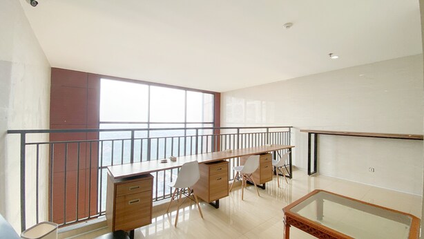 A spacious room with a large desk, chairs, a glass-top table, and a balcony with a railing. - Minimalist And Homey Studio At Evenciio Margonda Apartment (Depok)
