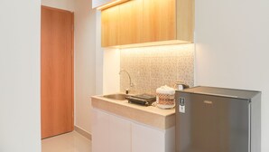 A compact kitchen with a built-in refrigerator, a sink, and a microwave. - Minimalist And Homey Studio At Evenciio Margonda Apartment (Depok)