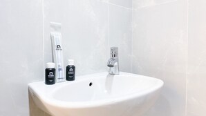 A bathroom with a white sink, a mirror, and toiletries including a toothbrush, toothpaste, and a bottle of shower gel. - Minimalist And Homey Studio At Evenciio Margonda Apartment (Depok)