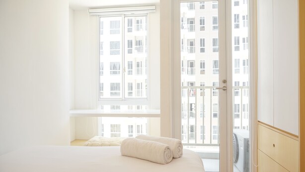 Une chambre à coucher avec un lit, une fenêtre et une porte donnant sur un balcon extérieur.