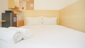 Une chambre d’hôtel avec un lit, une petite kitchenette et un lit parfaitement fait, agrémenté de serviettes blanches roulées.