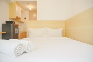 Cozy retreat with a neatly made bed, kitchenette, and modern amenities.