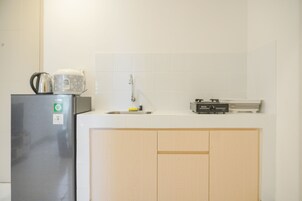 Una cocina con refrigerador, lavamanos y microondas.