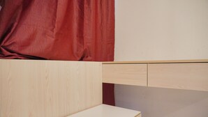 A corner of a room with a wooden desk and a white wall. - Minimalist And Comfy Studio At Tokyo Riverside Pik 2 Apartment (Teluknaga)
