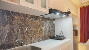 A modern kitchen with a marble backsplash, stainless steel sink, and wooden cabinets. - Minimalist And Comfy Studio At Tokyo Riverside Pik 2 Apartment (Teluknaga)