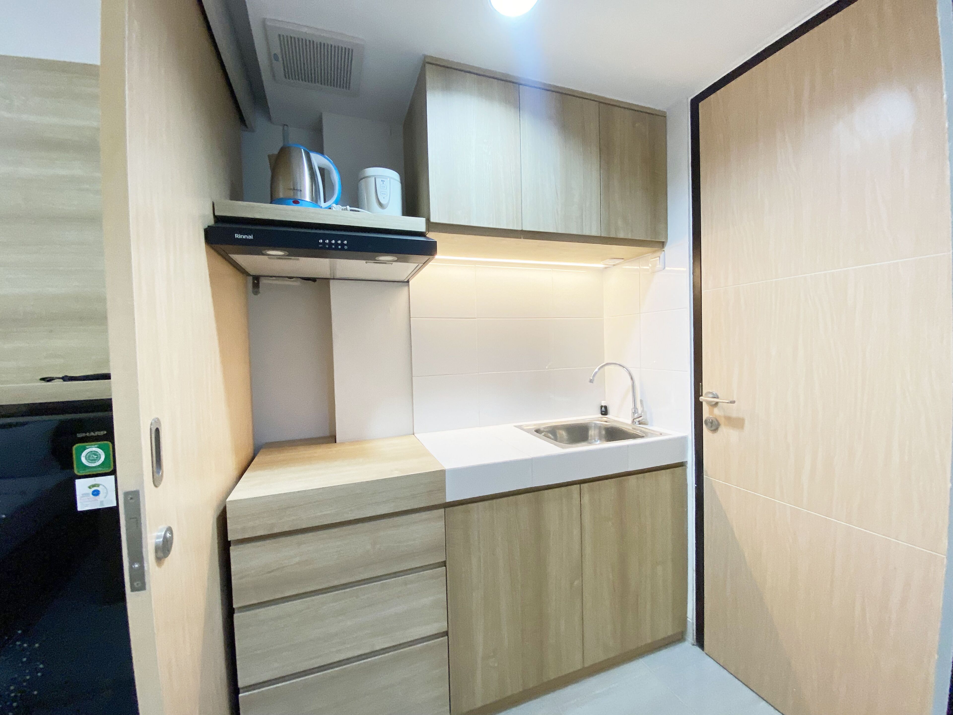 A compact kitchen with a sink, a coffee maker, and a kettle on the countertop.