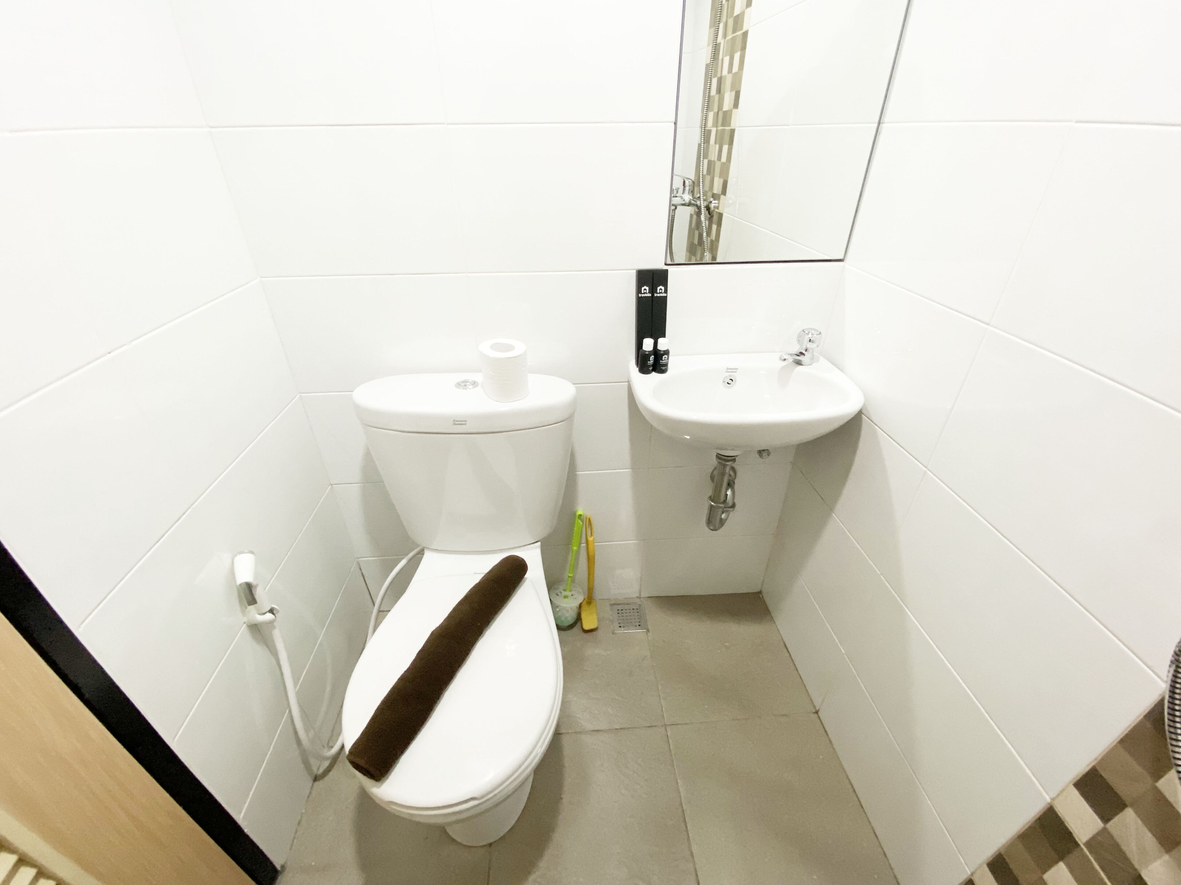 Een kleine, schone badkamer met toilet, wastafel en spiegel.