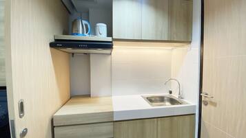 A compact kitchenette with a sink, a kettle, and a coffee maker on a countertop.