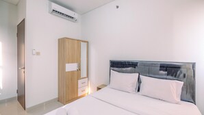 A bedroom with a bed, a wooden wardrobe, and an air conditioning unit. - New Furnished And Homey 2Br At Transpark Cibubur Apartment (Depok)