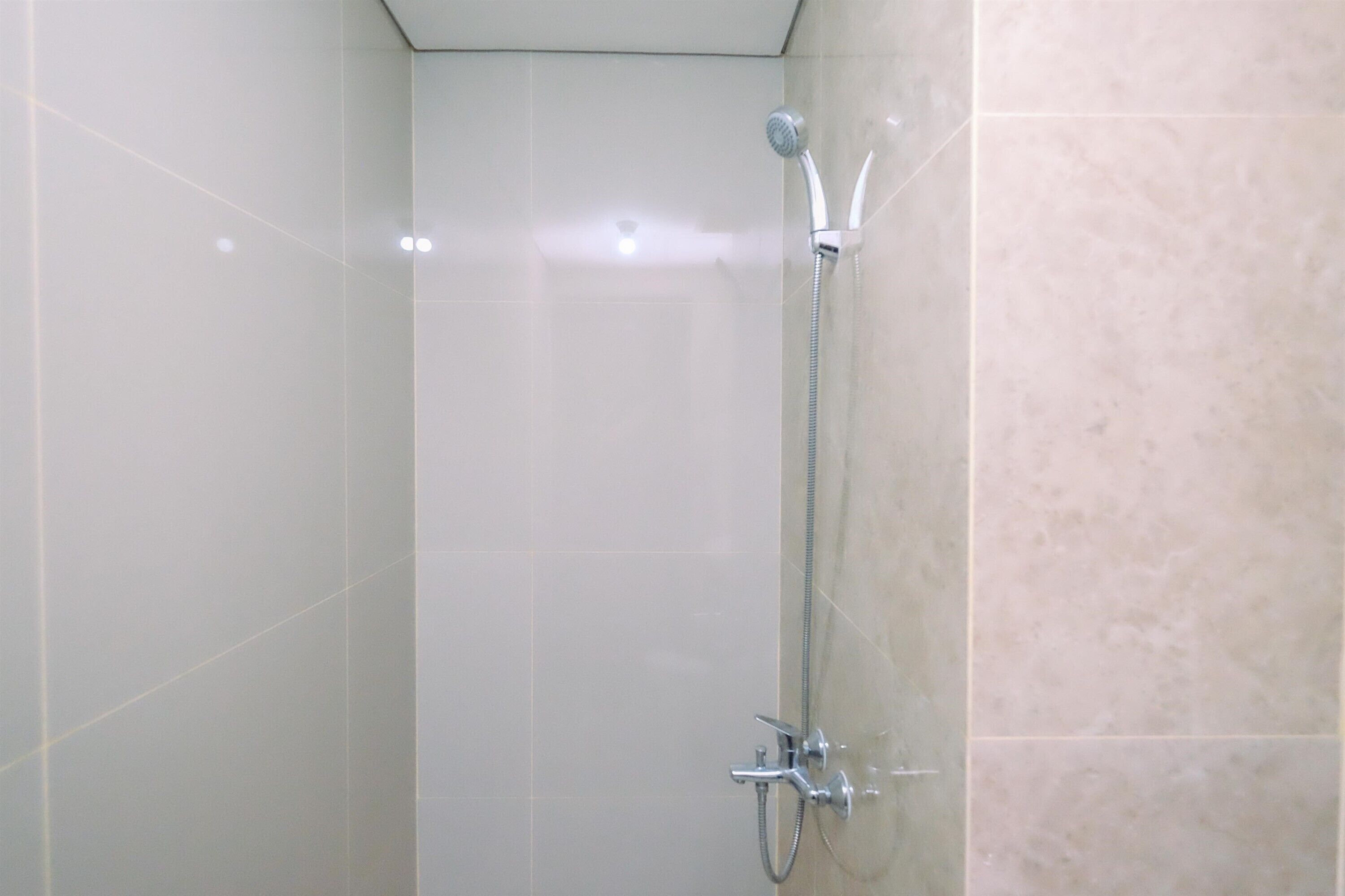 A shower with a handheld showerhead and a wall-mounted faucet.