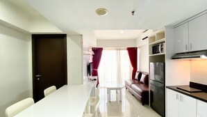 A modern kitchen with white cabinets, a stainless steel refrigerator, and a black countertop.