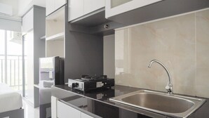A modern kitchen with a black countertop, stainless steel sink, and white cabinets.