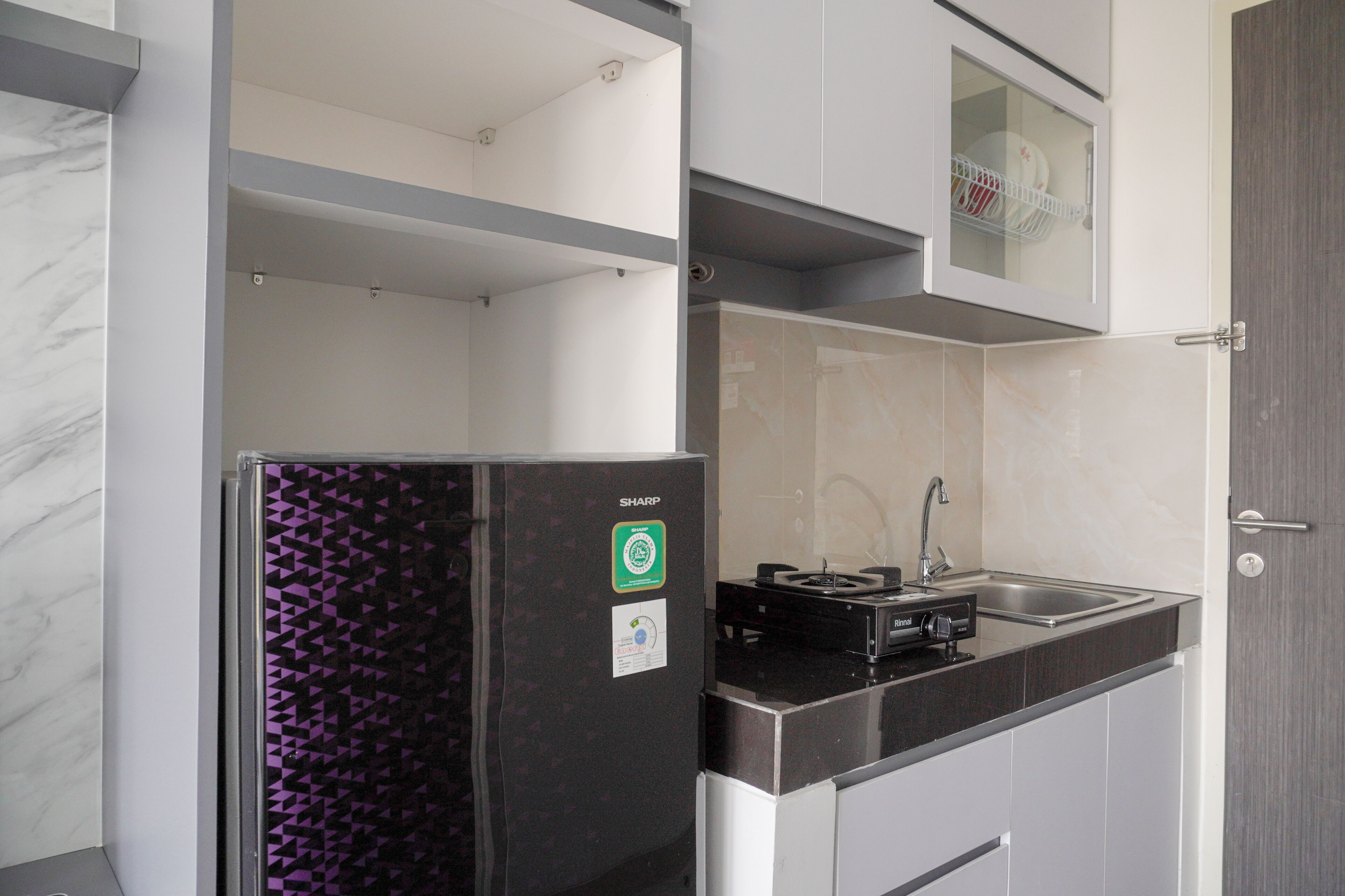 A modern kitchen with a black refrigerator, a built-in stove, and a sink.