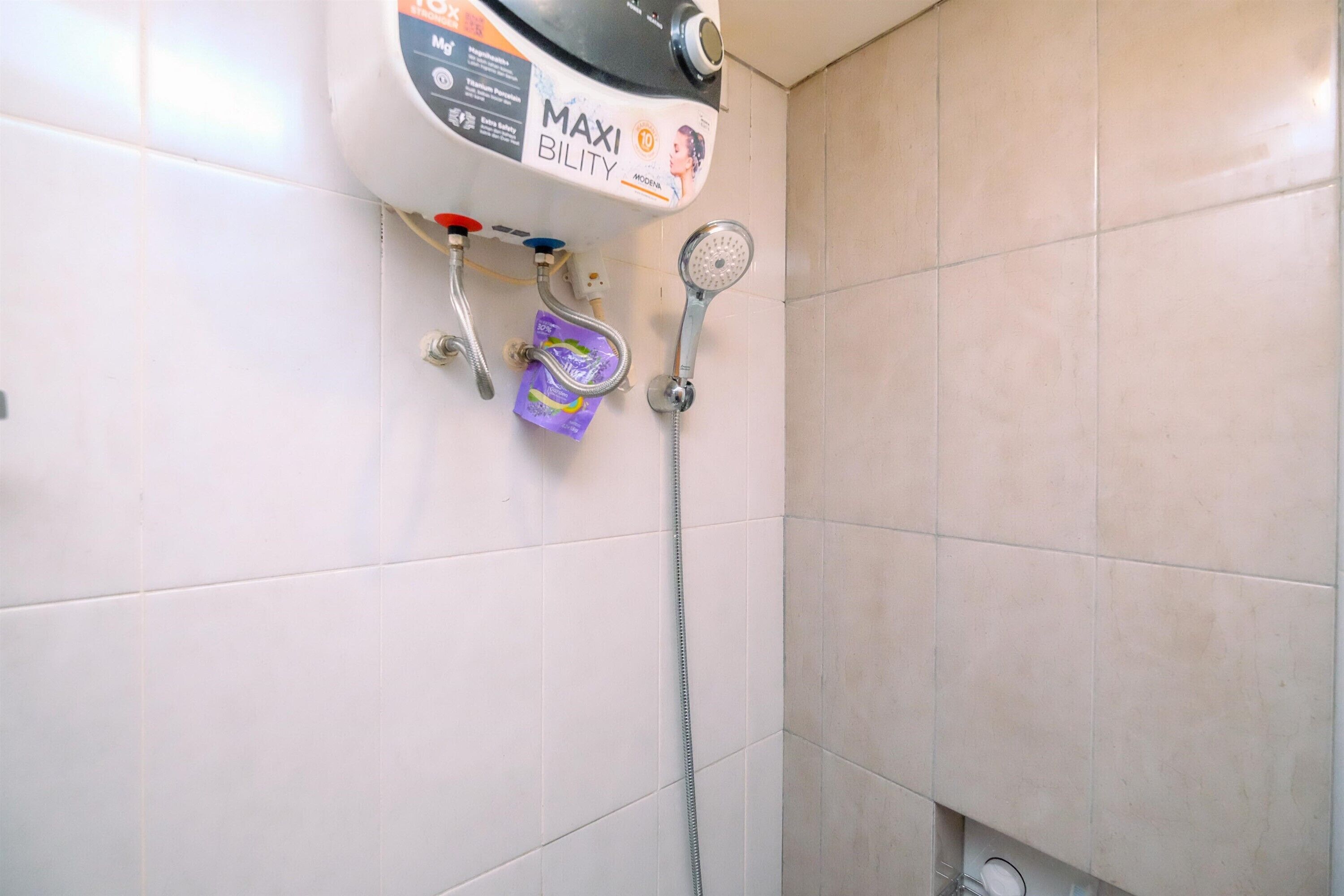 Een badkamer met een douche, een boiler en een zeepdispenser.