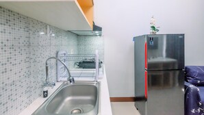 Eine kleine Küche mit Edelstahlkühlschrank, Spüle und gefliestem Fliesenspiegel.