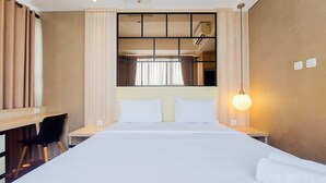 Une chambre d’hôtel avec un grand lit, un bureau et une chaise. Il y a une fenêtre avec des rideaux, un climatiseur fixé au mur et un luminaire fixé au mur.