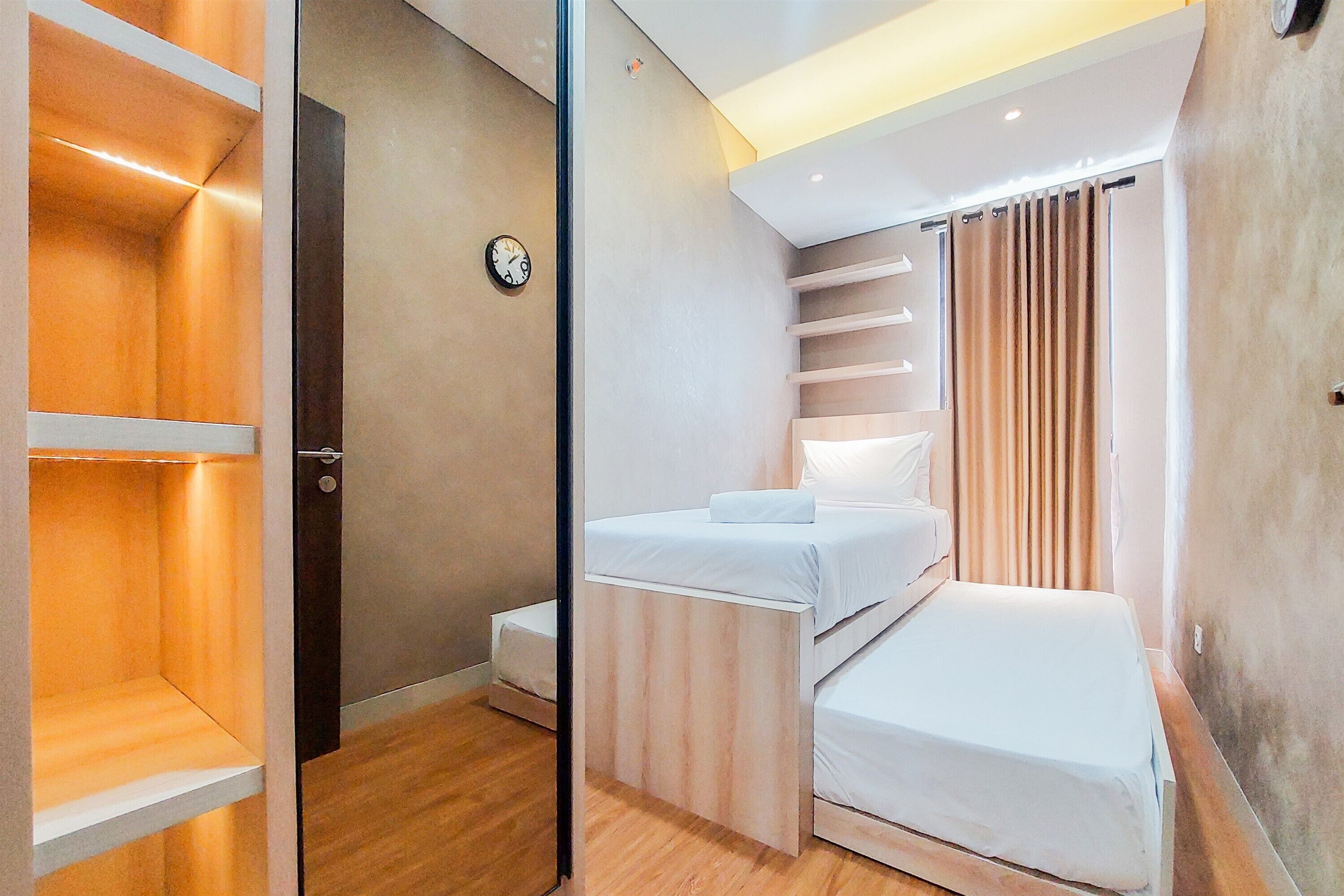 A compact bedroom with a bed, a small bedside table, a clock on the wall, and a sliding door leading to a closet.