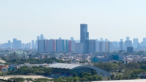 A cityscape with a prominent skyscraper, residential buildings, and a stadium. - Best Choice And Homey Studio Tifolia Apartment (Jakarta)