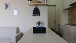 A modern kitchen with a light wood countertop, a built-in sink, and a black wall-mounted shelf with two water bottles. - Spacious 2Br At Grand Asia Afrika Apartment (Bandung)