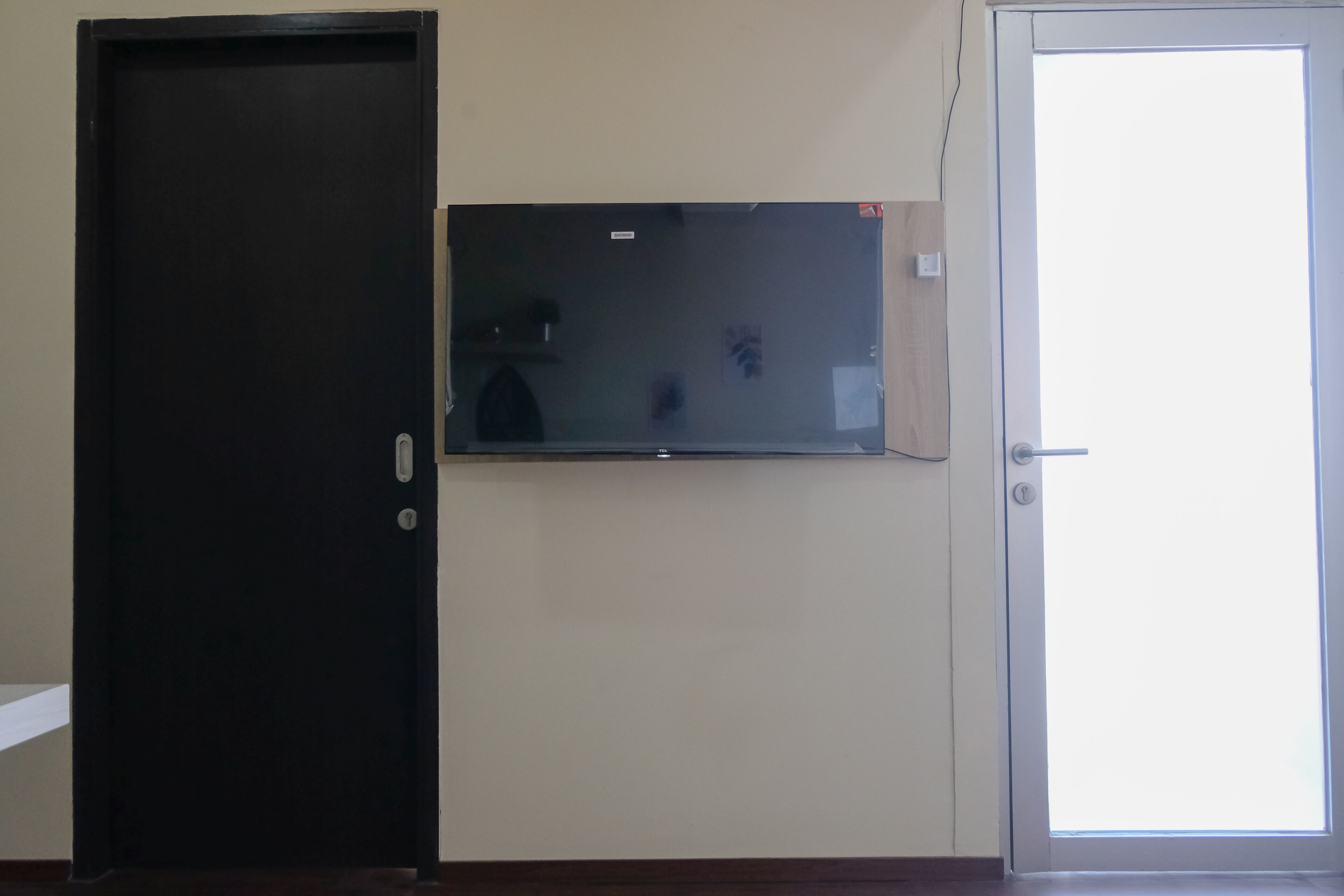 A room with a closed dark door, a glass partition, and a white door.