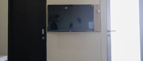 A room with a closed dark door, a glass partition, and a white door.