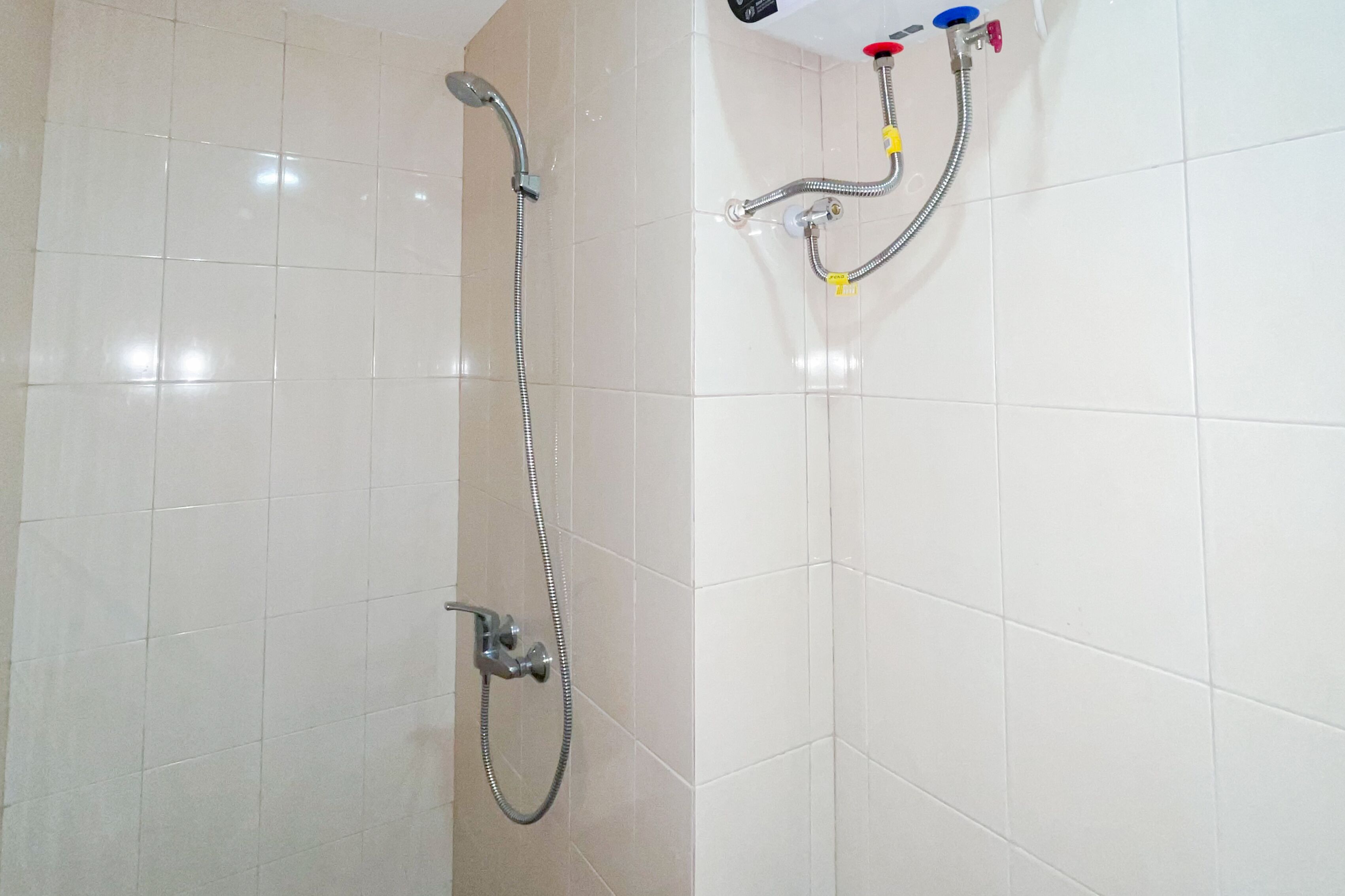 A shower area with a handheld showerhead and a wall-mounted faucet.
