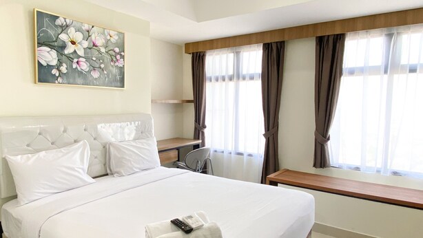 Ein Hotelzimmer mit einem großen Bett, einem Schreibtisch und einem Fenster mit Vorhängen.