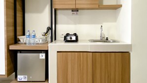 Eine kleine Küchenzeile mit integriertem Kühlschrank, Spüle und Holzschränken.
