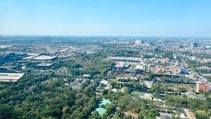 Eine Vogelperspektive einer Stadt mit einer Mischung aus Wohn- und Geschäftshäusern, Grünflächen und einer markanten Kuppelstruktur.
