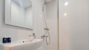 A bathroom with a white sink, mirror, and shower. - Scenic And Homey Studio Barsa City Apartment (Yogyakarta)