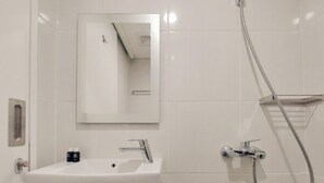 A bathroom with a white sink, a mirror, and a shower. - Scenic And Homey Studio Barsa City Apartment (Yogyakarta)