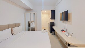 A modern hotel room with a large bed, a desk with a flat-screen TV, and a walk-in closet. - Scenic And Homey Studio Barsa City Apartment (Yogyakarta)