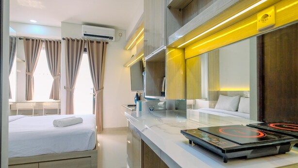 Una habitación de hotel moderna con cama, baño con espejo y encimera con cafetera.
