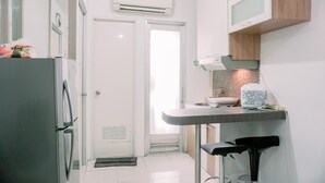 A kitchen with a refrigerator, a sink, and a bar stool. - Stunning And Homey 2Br Green Bay Pluit Apartment (Jakarta)