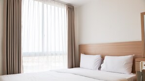 A hotel room with a large bed, a wooden headboard, and a view through sheer curtains. - Comfortable Stay 2Br Apartment At Tokyo Riverside Pik 2 (Teluknaga)
