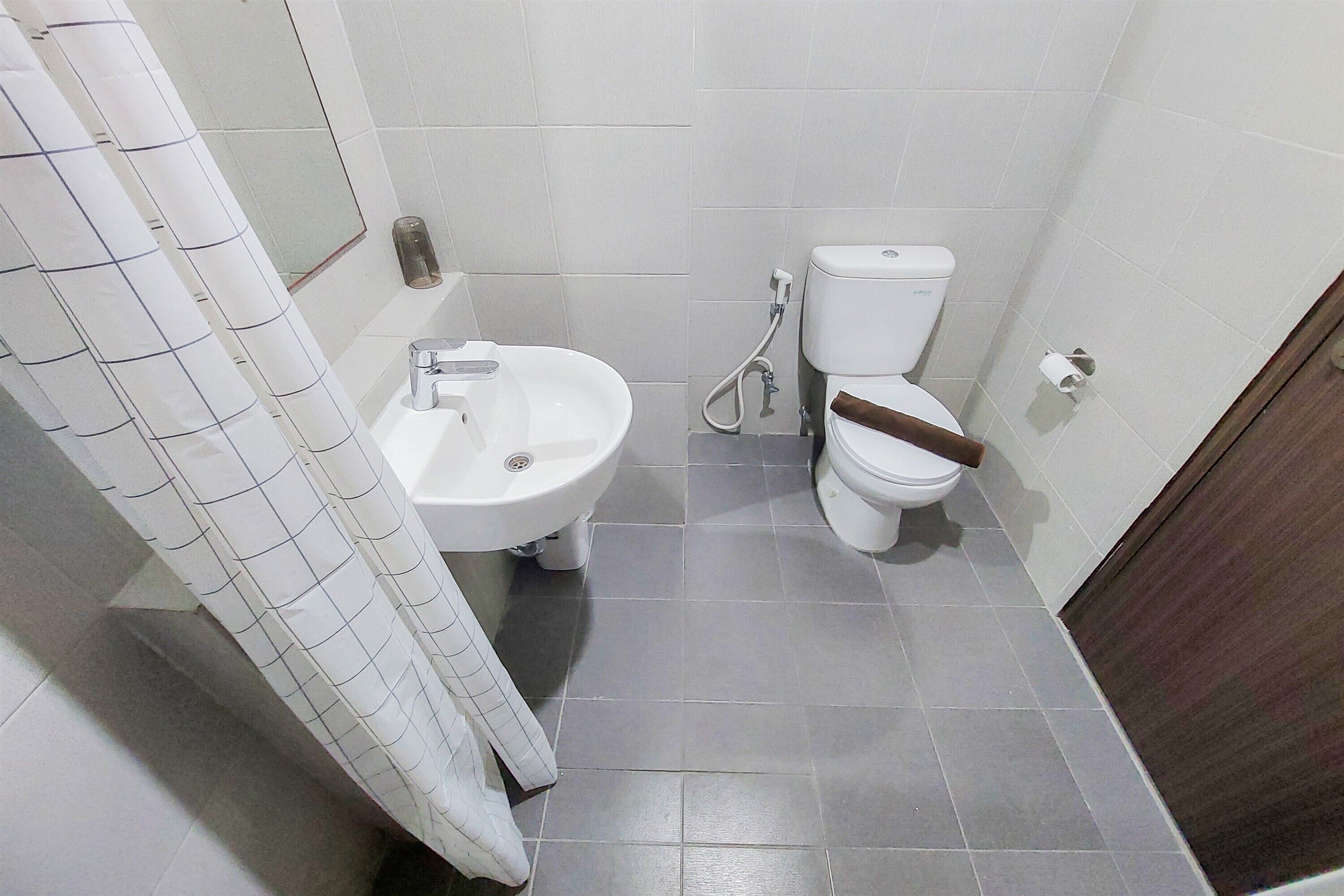 Un baño con lavamanos, inodoro y cortina de ducha blancos.