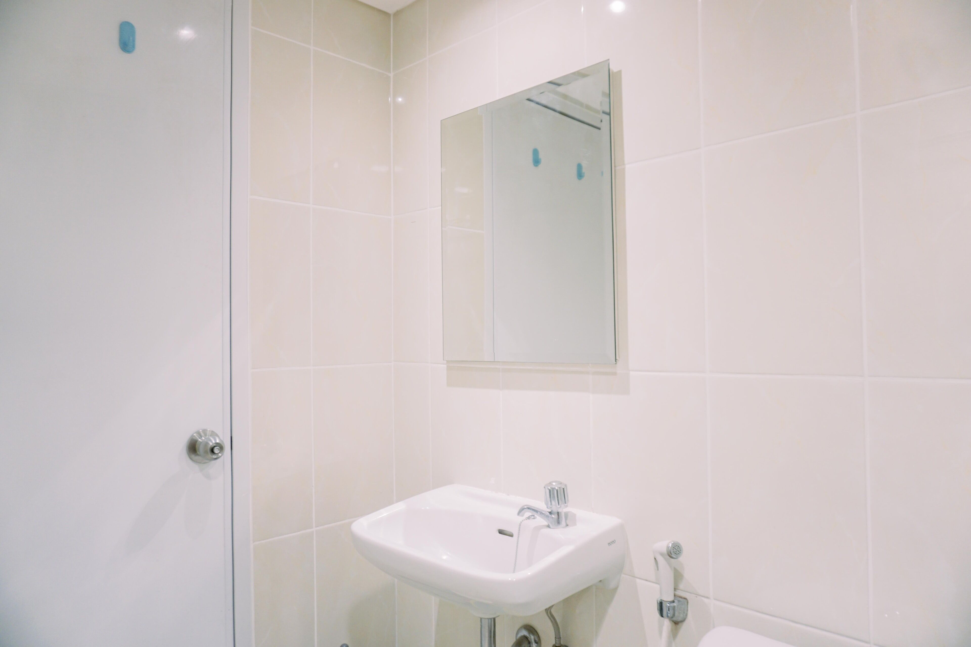 Une salle de bain avec un lavabo blanc, un miroir et une cabine de douche en verre.