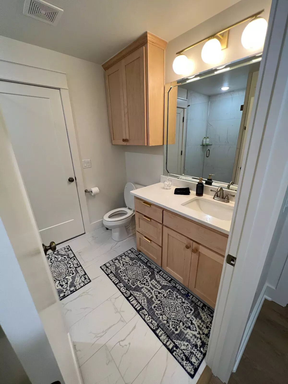 Une salle de bain équipée de toilettes, d’un lavabo, d’un miroir et de meubles en bois.