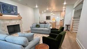 A living room with a fireplace, a sofa set, a coffee table, and a staircase leading to another level.
