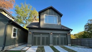 A two-story house with a garage, a covered patio, and a well-maintained lawn.