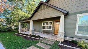 A house with a covered porch, stone pillars, and a front door.