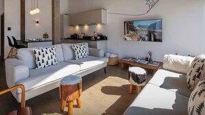 Een moderne woonkamer met een bank, salontafel en een eethoek met stoelen, en een keuken op de achtergrond.