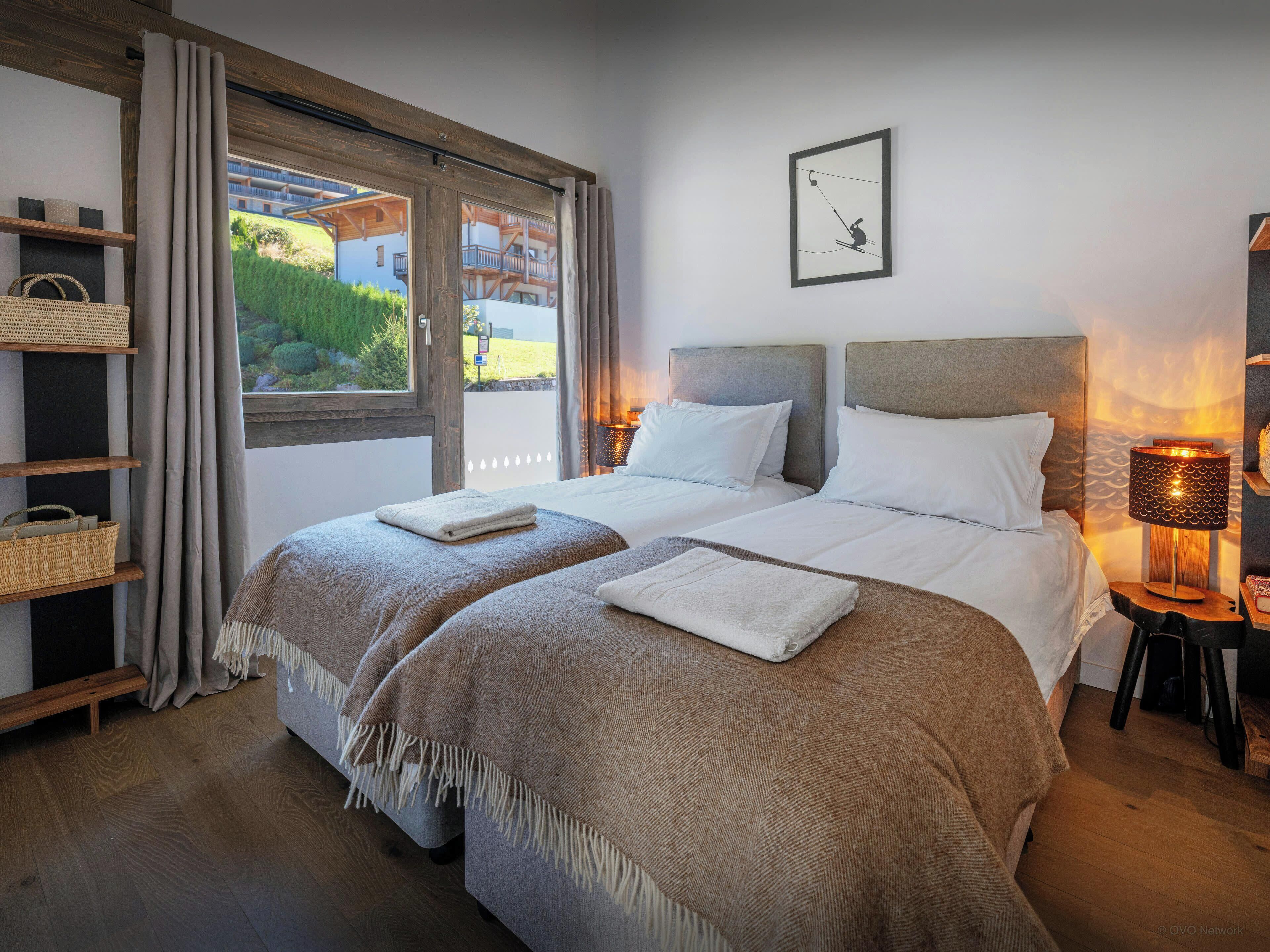 Una cama doble con cabecera, una mesita de noche con lámpara, una ventana con cortinas y un cuadro colgado en la pared.