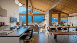 Een moderne keuken met een groot eiland, houten balken en uitzicht op bergen.