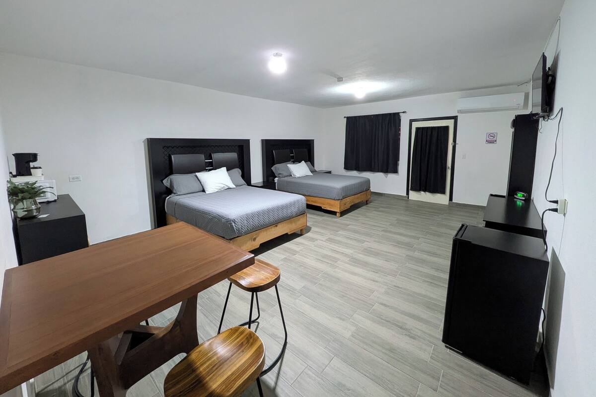 Une chambre moderne avec deux lits, une table en bois et un bureau avec un ordinateur.