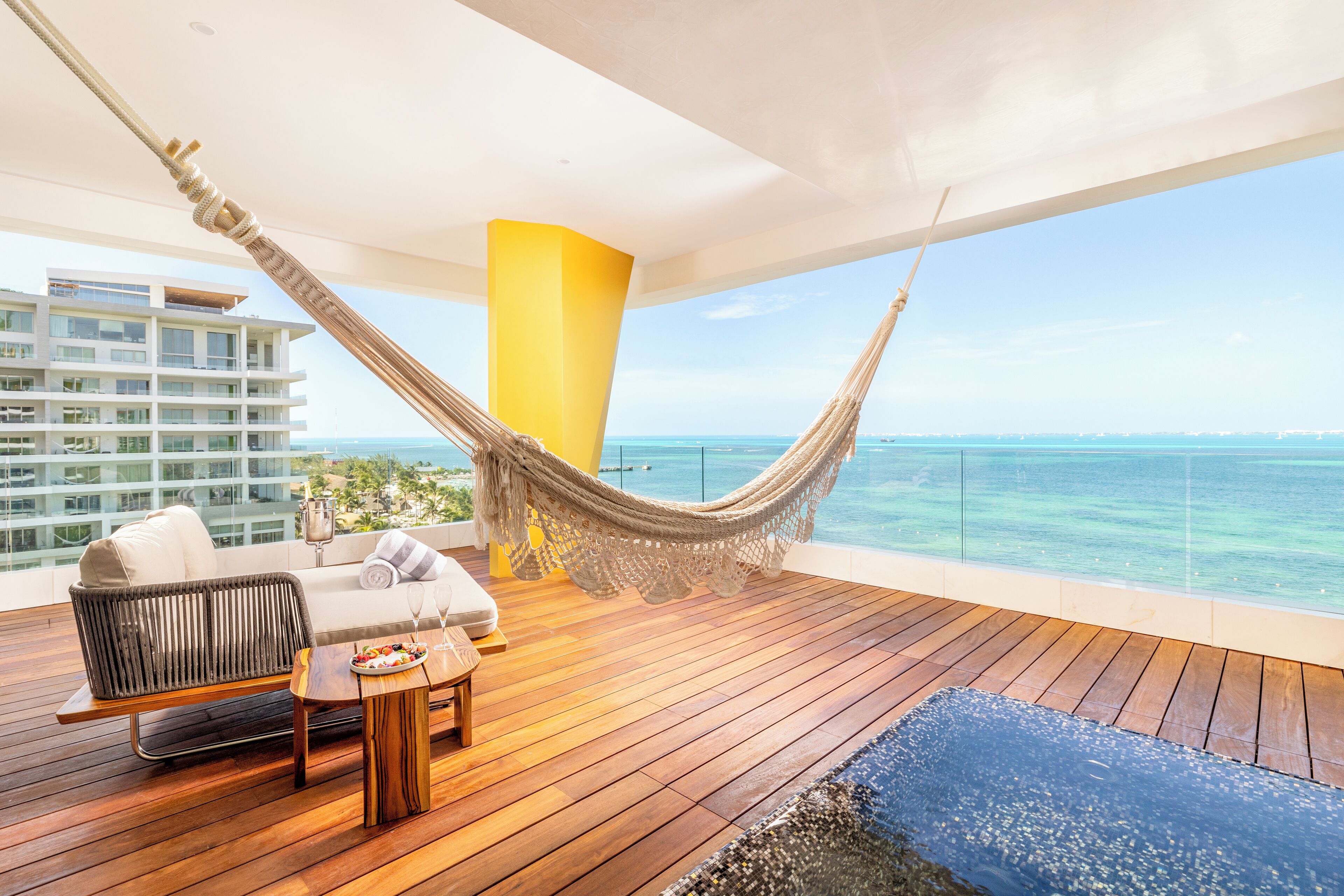 A wooden deck with a hammock, a sofa, and a table with snacks.