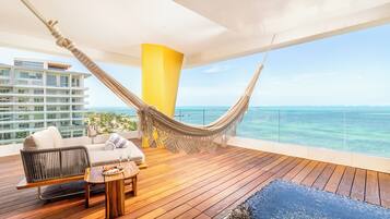 A wooden deck with a hammock, a sofa, and a table with snacks.