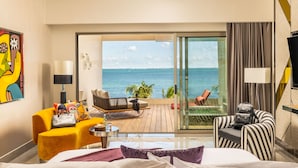 A hotel room with a bed, a yellow armchair, a striped armchair, a small table with a lamp, and a view of the sea through a sliding glass door. - Hotel Mousai Cancun Adults Only - All Inclusive (Punta Sam)