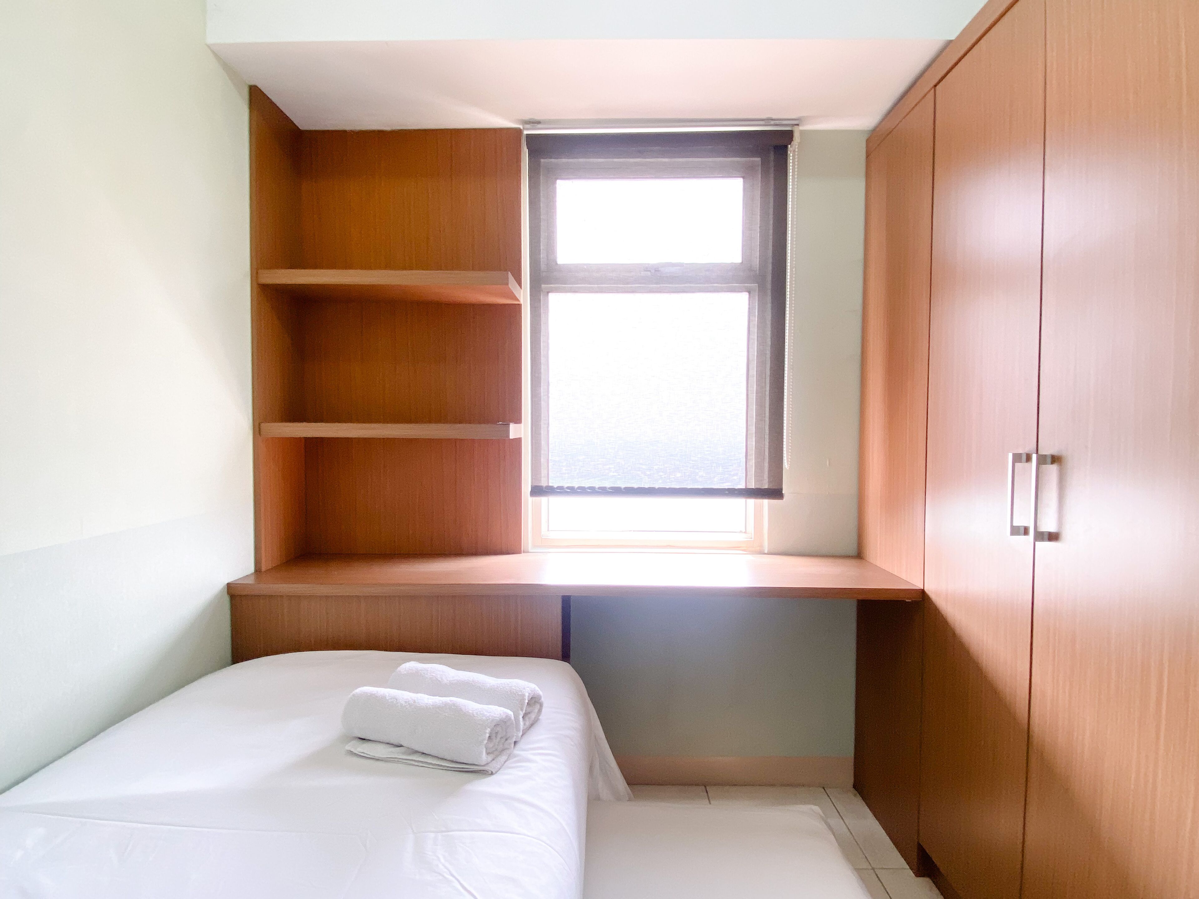A bedroom with a bed, a window, and built-in wooden shelving.